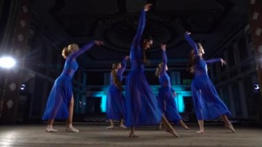 Grup genç yetenekli balerinler büyük salon sahnede modern bale dans. Kızlar oditoryuma bakıyor. Performans öncesi kostümlü prova.