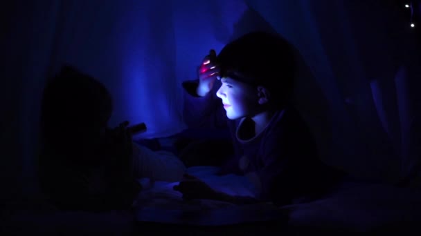 毛布の下に小さな子供たちは、懐中電灯でお互いに輝きます。スローモーション — ストック動画