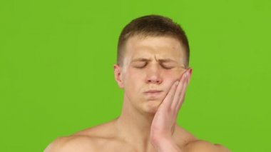 Adam diş ağrısından muzdarip ve çenesini eliyle ovuyor. Yakın çekim.