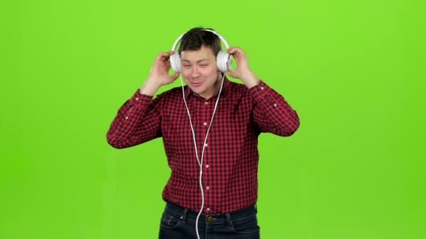 El hombre escucha música a través de auriculares, bailes. Pantalla verde. Movimiento lento — Vídeos de Stock