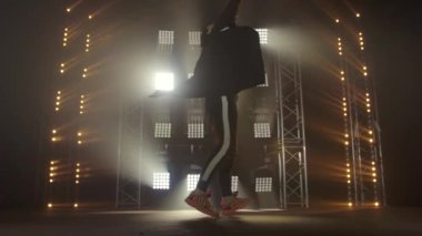 Breakdance konsepti. Genç adam kulüpte tek başına dans ediyor, neon ışıklı, dumanlı. Moda sokak kıyafeti..