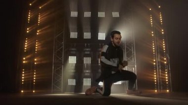 Breakdance konsepti. Genç adam kulüpte tek başına dans ediyor, neon ışıklı, dumanlı. Moda sokak kıyafeti..