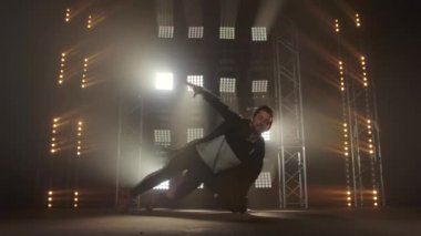 Breakdance konsepti. Genç adam kulüpte tek başına dans ediyor, neon ışıklı, dumanlı. Moda sokak kıyafeti..