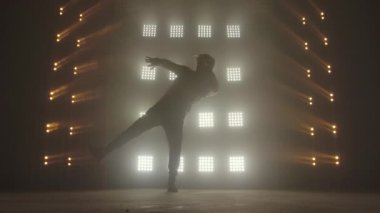Breakdance konsepti. Genç adam kulüpte tek başına dans ediyor, neon ışıklı, dumanlı. Moda sokak kıyafeti..