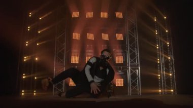 Breakdance konsepti. Genç adam kulüpte tek başına dans ediyor, neon ışıklı, dumanlı. Moda sokak kıyafeti..
