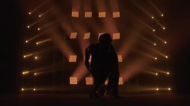 Breakdance konsepti. Genç adam kulüpte tek başına dans ediyor, neon ışıklı, dumanlı. Moda sokak kıyafeti..