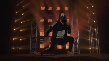 Breakdance konsepti. Genç adam kulüpte tek başına dans ediyor, neon ışıklı, dumanlı. Moda sokak kıyafeti..