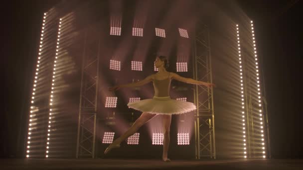 Επαγγελματική μπαλαρίνα χορού μπαλέτο σε προβολείς καπνού στη μεγάλη σκηνή. Όμορφη νεαρή κοπέλα φορώντας λευκό φόρεμα tutu σε φόντο προβολείς — Αρχείο Βίντεο