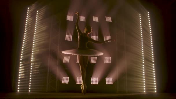 Sahne ışıkları altında dans eden profesyonel balerin büyük sahnede sigara içiyor. Sahne ışıkları altında beyaz etek giyen güzel bir kız. — Stok video