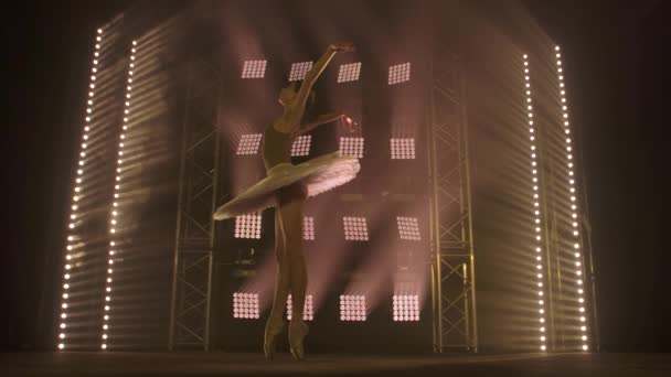 Bailarina profesional bailando ballet en focos de humo en el gran escenario. Hermosa joven con vestido de tutú blanco en los reflectores de fondo — Vídeo de stock