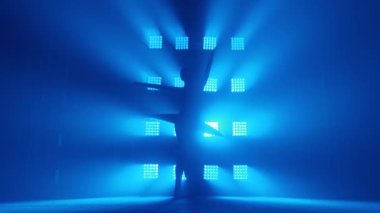 Zarif siluet balerin sınıfta antrenman yapıyor. Mavi ışıkta duman çıkıyor. Beyaz etekli balerin, noktalı kız, etrafında dönüyor, ağır çekimde.