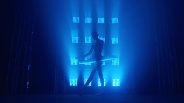 Bailarina de silueta elegante haciendo un entrenamiento en el aula. Humo en los rayos de luz azul. Bailarina de ballet en tutú blanco, chica en punta, gira a tu alrededor, cámara lenta — Vídeo de stock