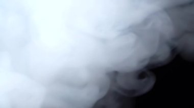 Beyaz duman siyah arka planda uzayda süzülüyor. Sis, duman, buhar, sis etkisi. Yavaş çekim