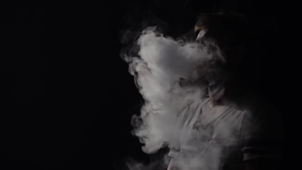 Jonge man met baard roken hookah, uitademen witte rook op zwart geïsoleerde achtergrond in slow motion. — Stockvideo