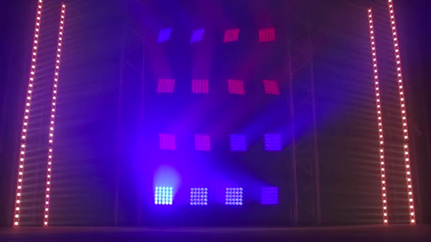 O palco de um pequeno teatro com holofotes vermelhos e azuis. As luzes estão acesas da escuridão. . — Vídeo de Stock