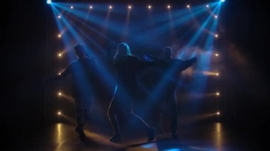 Yetenekli genç hip hop dansçılarının siluetleri. Karanlık bir stüdyoda, dumanlı ve neon ışıklı bir sahnede hip hop sokak dansı. Dinamik ışıklandırma efektleri. Yaratıcı yetenekler. Yavaş çekim.