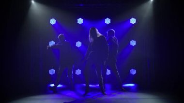 Yetenekli genç hip hop dansçılarının siluetleri. Karanlık bir stüdyoda, dumanlı ve neon ışıklı bir sahnede hip hop sokak dansı. Dinamik ışıklandırma efektleri. Yaratıcı yetenekler. Yavaş çekim.