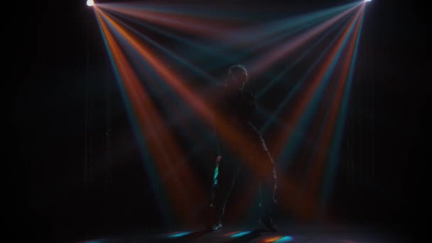 Silhouet van een getalenteerde jonge hiphopdanseres. Hip hop straat dans op een podium in donkere studio met rook en neon verlichting. Dynamische lichteffecten. Creatieve vaardigheden. Langzame beweging. — Stockvideo
