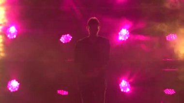 Yetenekli genç bir hip hop dansçısının silueti. Karanlık bir stüdyoda, dumanlı ve neon ışıklı bir sahnede hip hop sokak dansı. Dinamik ışıklandırma efektleri. Yaratıcı beceriler.