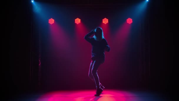 Silhouet van een getalenteerde jonge hiphopdanseres. Hip hop straat dans op een podium in donkere studio met rook en neon verlichting. Dynamische lichteffecten. Creatieve vaardigheden. Langzame beweging. — Stockvideo