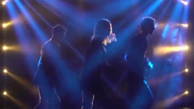 Yetenekli genç hip hop dansçılarının siluetleri. Karanlık bir stüdyoda, dumanlı ve neon ışıklı bir sahnede hip hop sokak dansı. Dinamik ışıklandırma efektleri. Yaratıcı beceriler.