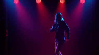 Yetenekli genç bir hip hop dansçısının silueti. Karanlık bir stüdyoda, dumanlı ve neon ışıklı bir sahnede hip hop sokak dansı. Dinamik ışıklandırma efektleri. Yaratıcı beceriler.