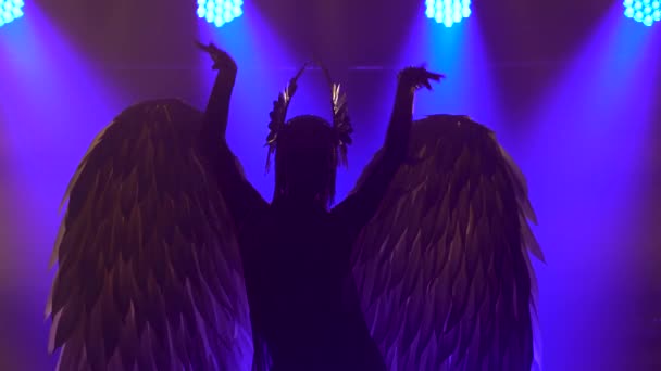 Silhouette der tanzenden griechischen Göttin Artemis mit Flügeln auf der Bühne in einem dunklen Studio mit Rauch und Neonlicht. Leuchtende Neonlichteffekte. Luxuriöse Theateraufführung Vokal- und Tanzshow. — Stockvideo