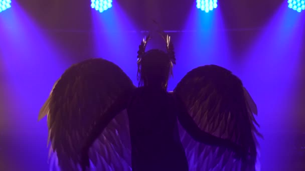 Silhouette der tanzenden griechischen Göttin Artemis mit Flügeln auf der Bühne in einem dunklen Studio mit Rauch und Neonlicht. Leuchtende Neonlichteffekte. Luxuriöse Theateraufführung Vokal- und Tanzshow. — Stockvideo