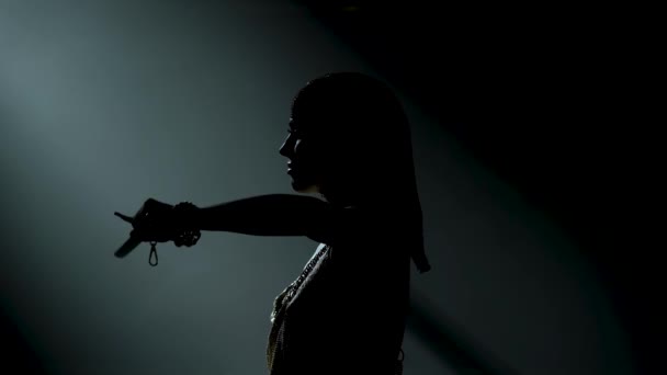 Silueta tančící řecké bohyně Artemis na jevišti v tmavém studiu s kouřem a neonovým osvětlením. Jasná mladá žena s mečem ve zlatých šatech a čelenkou. Dynamické neonové světelné efekty — Stock video