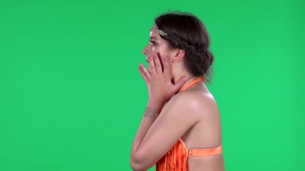 Portret van mooie jonge vrouwen met geschokte en verbaasde wow face expressie. Een brandende brunette in een oranje franje op een groen scherm in de studio. Zijaanzicht. — Stockvideo