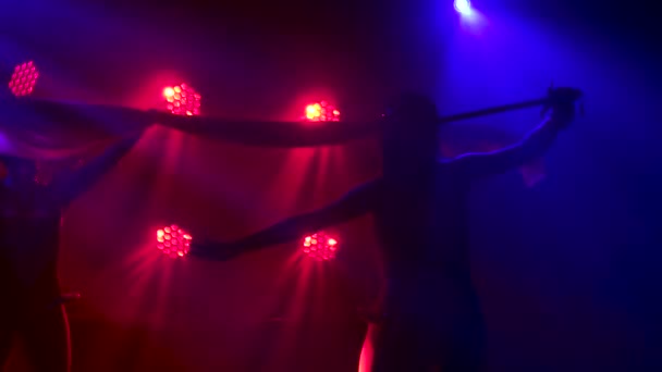 Silueta tančící řecké bohyně Artemis na jevišti v tmavém studiu s kouřem a neonovým osvětlením. Jasná mladá žena s mečem ve zlatých šatech a čelenkou. Dynamické neonové světelné efekty — Stock video