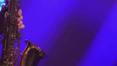 Sahnede altın gibi parlak saksafon çalan profesyonel müzisyen tuşları. Dumanlı ve neon ışıklı karanlık stüdyo. Kapat..