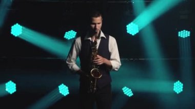 Genç, modaya uygun bir adam, sahnedeki turkuaz spot ışıklarıyla altın gibi parlak bir saksafonda çalar. Dumanlı ve neon ışıklı karanlık stüdyo.