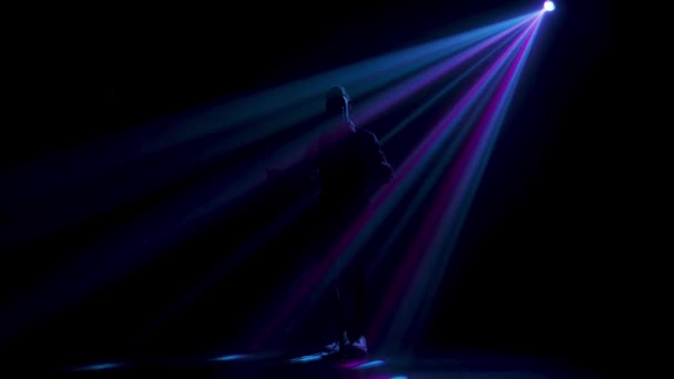 Silhouet een jonge stijlvolle zanger die zingt en gebaart met zijn handen op het podium in een vintage microfoon. Donkere studio met rook en neon verlichting. Dynamische neonverlichting effecten. Prestatie vocaal — Stockvideo