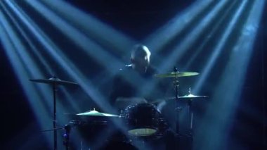 Karanlık bir stüdyoda, dumanlı ve neon ışıklı davul setinde davul çalan siluet davulcusu. Dinamik neon ışık efektleri. Performans vokali ve müzik grubu. Yakın plan..