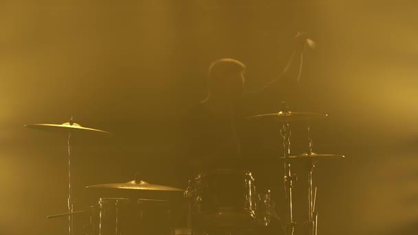 Silhouette baterista tocando en el kit de batería en el escenario en un estudio oscuro con humo e iluminación de neón. Banda vocal y musical. Primer plano. — Vídeo de stock