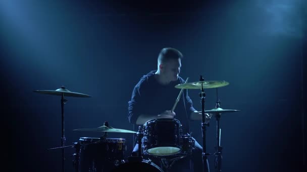 Silhouette batteur jouant sur batterie kit sur scène dans un studio sombre avec fumée et néon. Performance vocale et orchestre musical. Gros plan. — Video