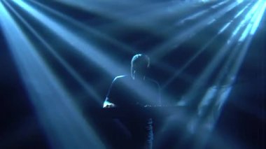 Karanlık stüdyoda, sentezleyici piyano klavyesinde neon ışıkla çalan müzisyen silueti. Dinamik neon ışık efektleri. Performans vokal ve müzik grubu.