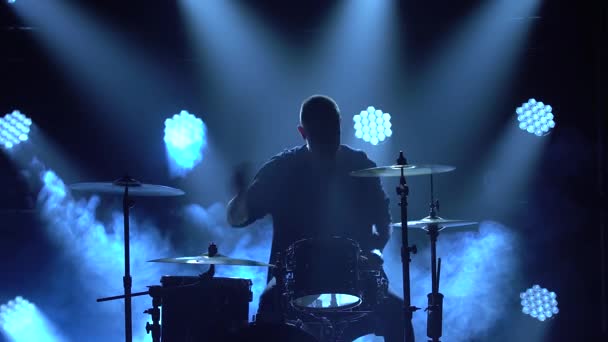 Baterista de silhueta tocando bateria no palco em um estúdio escuro com fumaça e iluminação de néon. Efeitos de iluminação de néon dinâmico. Performance vocal e banda musical. Close-up . — Vídeo de Stock