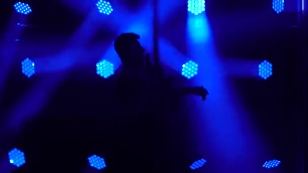 一个年轻人在一个黑暗的工作室的舞台上用电吉他弹奏的轮廓，这个工作室有烟雾弥漫的霓虹灯。动态蓝色霓虹灯照明效果. — 图库视频影像