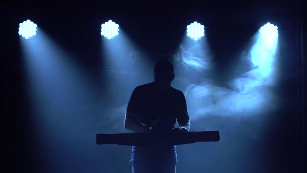 Silueta de músico tocando en sintetizador teclado de piano en estudio oscuro con iluminación de neón. Efectos de iluminación de neón. Banda vocal y musical de performance. — Vídeos de Stock