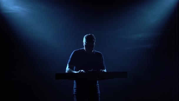 Silueta de músico tocando en sintetizador teclado de piano en estudio oscuro con iluminación de neón. Banda vocal y musical de performance. — Vídeos de Stock