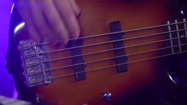 Duman ve neon ışıkla karanlık bir stüdyoda elektro gitarla çalan profesyonel bir müzisyen. Bir müzikalin iplerini elinde tutan bir adamın parmaklarını kapat. Dinamik neon ışıklandırma efektleri.