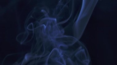 Soyut duman bulutu. Mavi duman yavaşça uzayda siyah arkaplana doğru süzülüyor. Kapatın. Yavaş çekim.