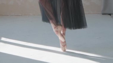 Siyah şeffaf etekli balerin klasik bale pas gösteriyor. Beyaz parke zeminde dans eden balerin ayak egzersizleri yapıyor. Kapat..