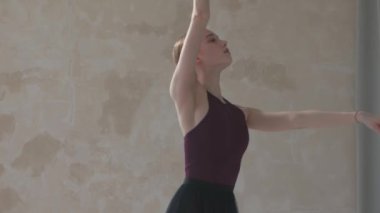 Siyah sahnede dans figürlerini prova eden genç ve güzel bir dansçı. Beyaz parke döşemeli stüdyoda dans dersi. Kapat..