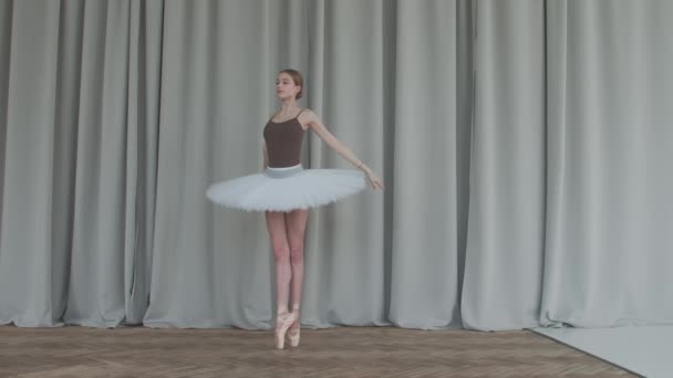 Dança bailarina flexível em uma escola de balé de dança clássica. Tiro no estúdio com cortinas de luz e piso em parquet no fundo. — Vídeo de Stock