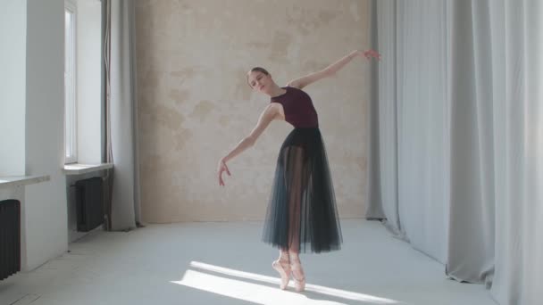 Performance einer fragilen Ballerina vor dem Hintergrund großer Panoramafenster und Vorhänge. Gedreht in einem Studio im Loft-Stil, das in helles Tageslicht getaucht ist. — Stockvideo