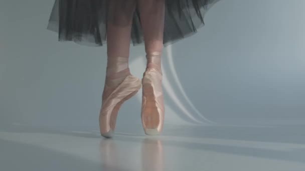 Ballerine dans une jupe transparente noire montre ballet classique pas. Les danseurs de ballet pieds comme elle pratique des exercices de pointe sur les planchers blancs. Gros plan. — Video