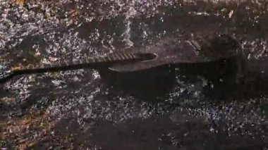 Gitar karanlık bir stüdyoda suyun yüzeyine düşer. Gitarda yağmur davulları çalıyor ve farklı yönlere püskürtüyor. Kapatın. Yavaş çekim.